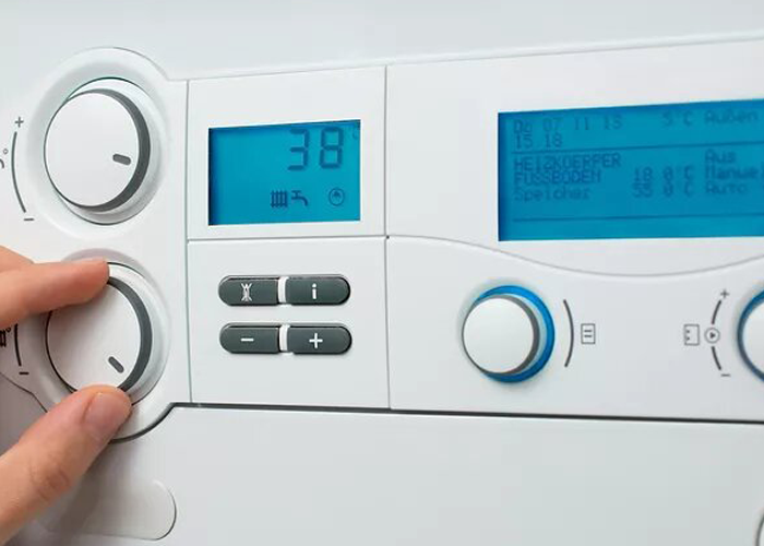 person adjusting an AC wall thermostat